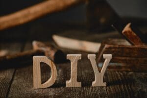 Close up view of diy sign on wooden table on the background of tools and logs