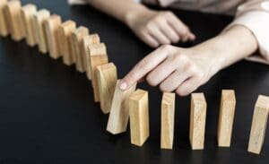 Hand knocking down a line of dominoes - representing the domino effect of learning strategies.